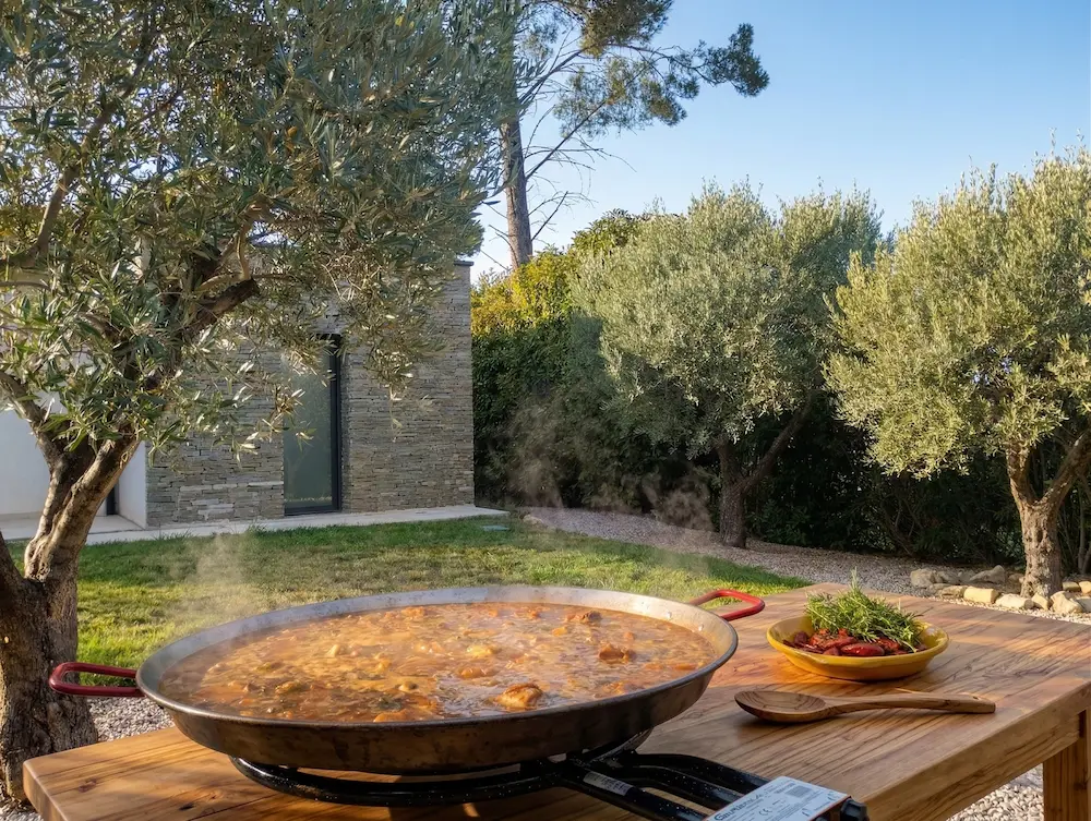 Paella en cuisson avec vapeur dans un jardin avec oliviers — Sabor Paella Montpellier